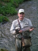 Man stands in creek with large rainbow trout